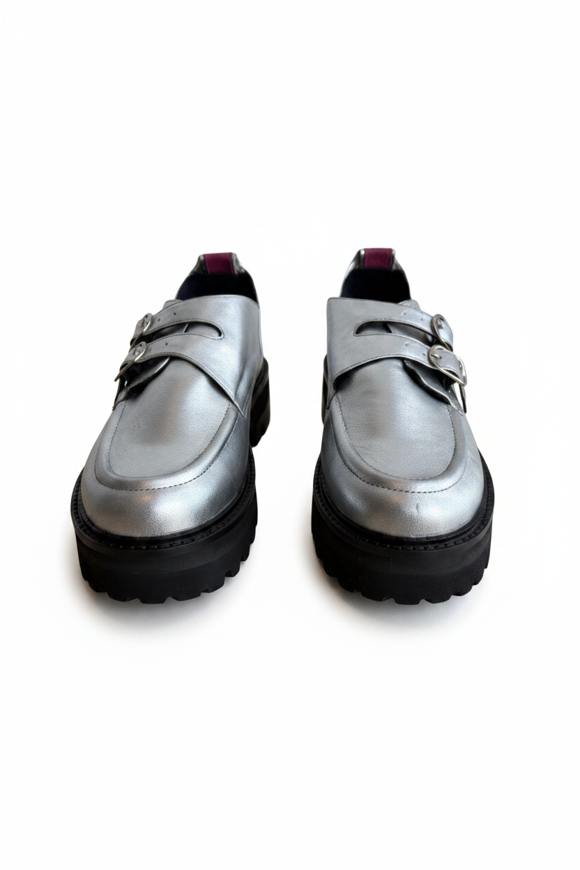 A pair of metallic silver platform loafers with double strap buckles and chunky black soles, shown against a plain white background.