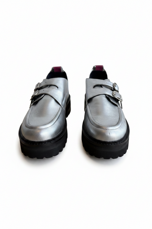 A pair of metallic silver platform loafers with double strap buckles and chunky black soles, shown against a plain white background.