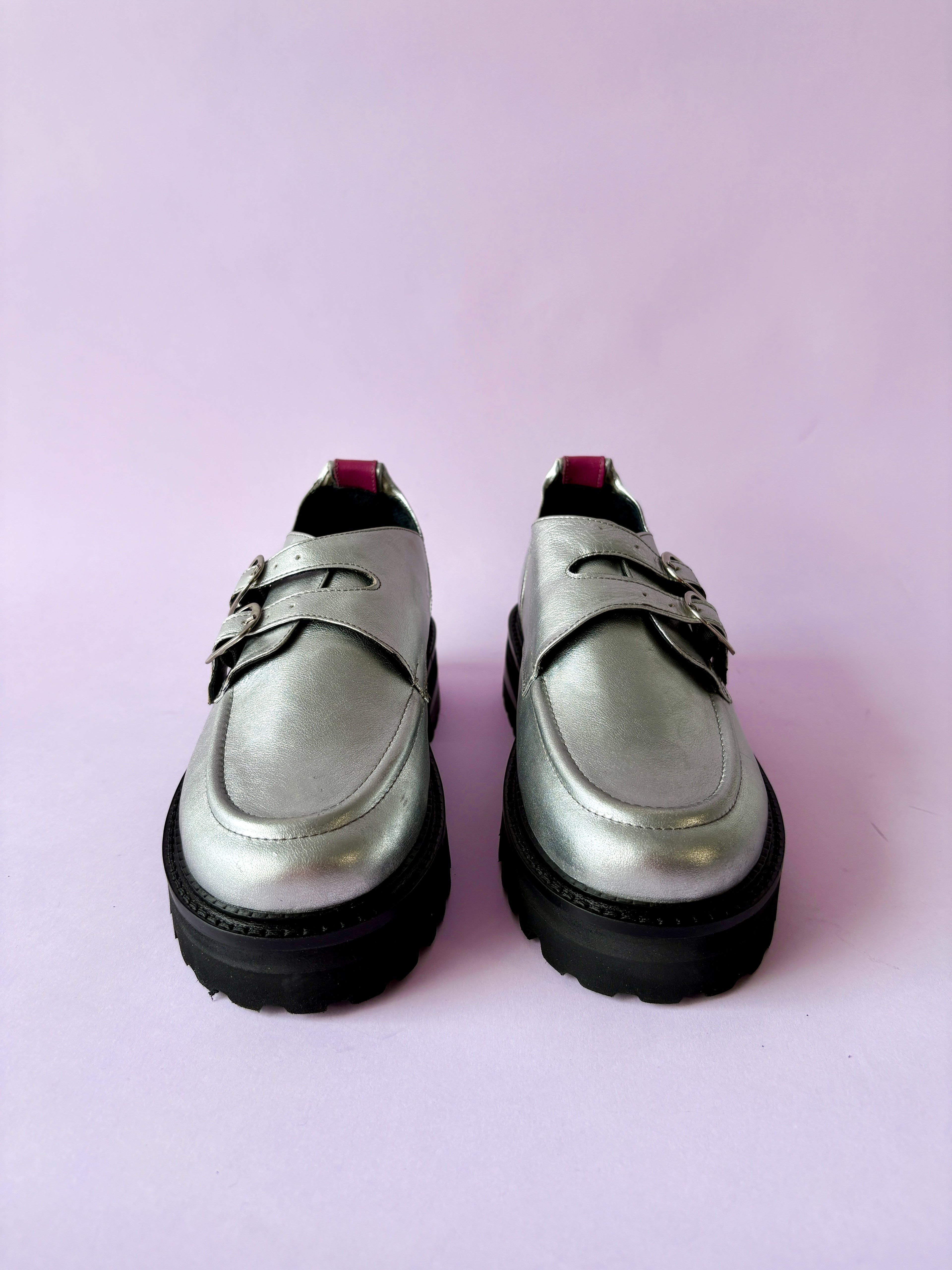 Mocasines plateados con suela negra en fondo rosado