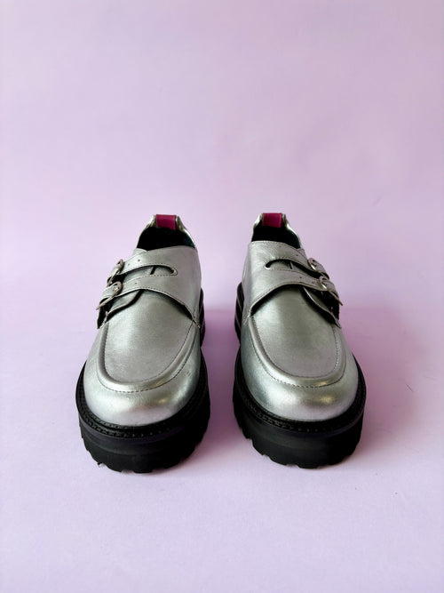 Mocasines plateados con suela negra en fondo rosado