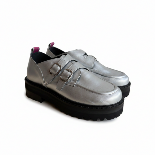 A pair of metallic silver leather double-strap loafers with chunky black lug soles, shown against a plain white background.